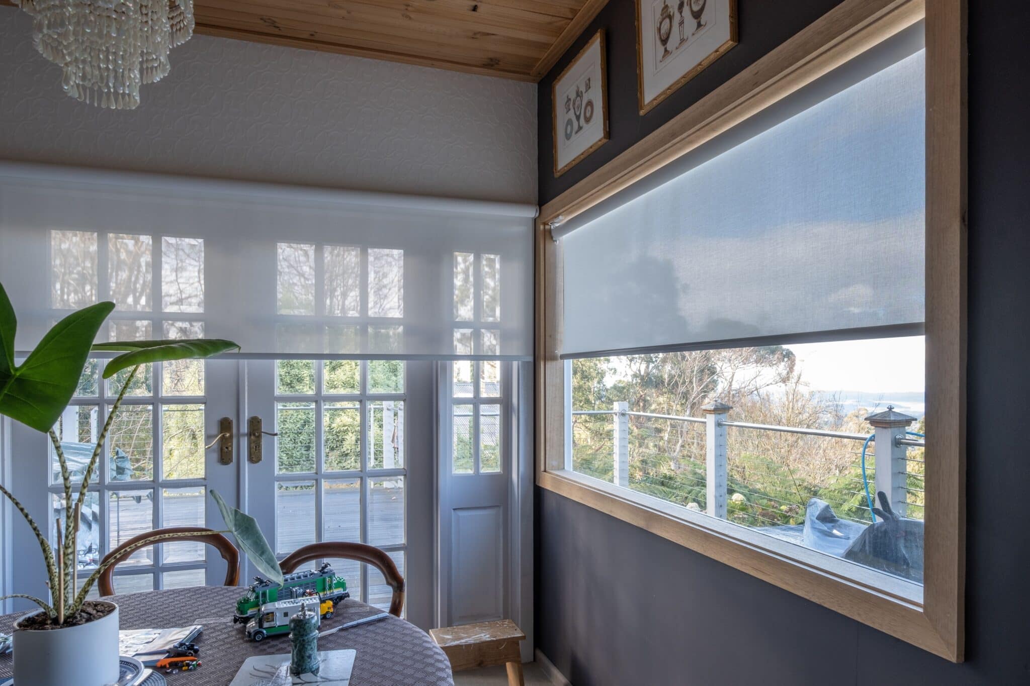 Light-filtering roller blinds in a cosy Adelaide dining room with a scenic outdoor view.