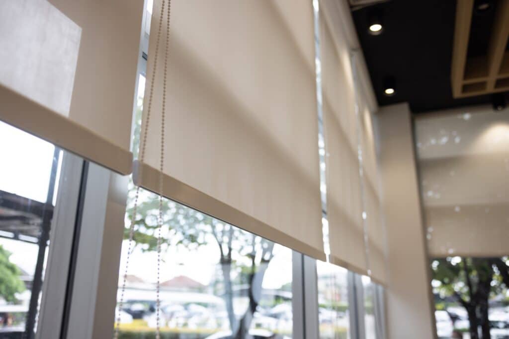 Close-up of beige roller blinds on large commercial windows in Adelaide.