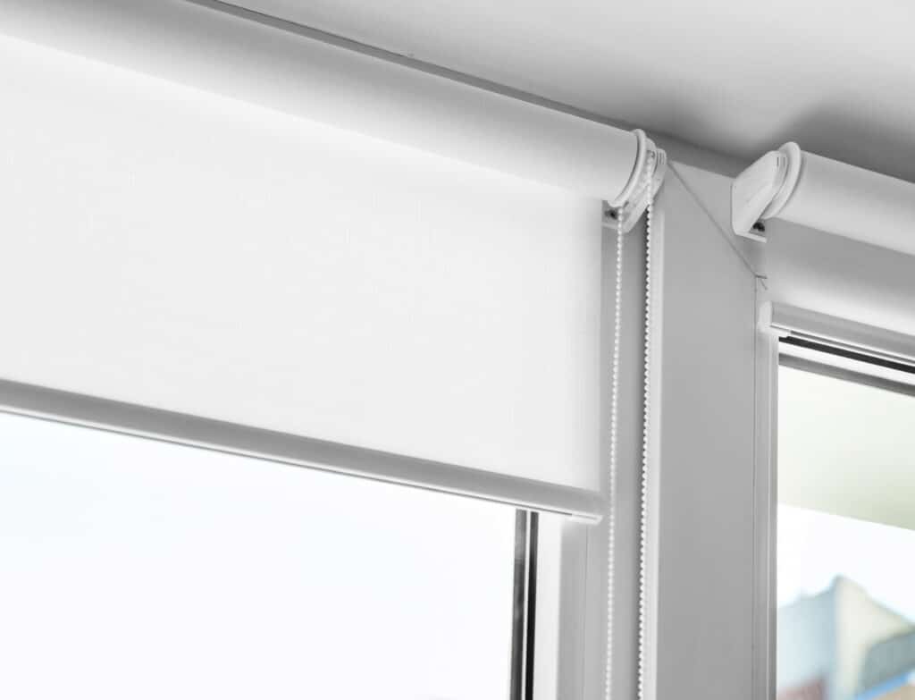 Close-up of white roller blinds with chain control on a modern Adelaide window.