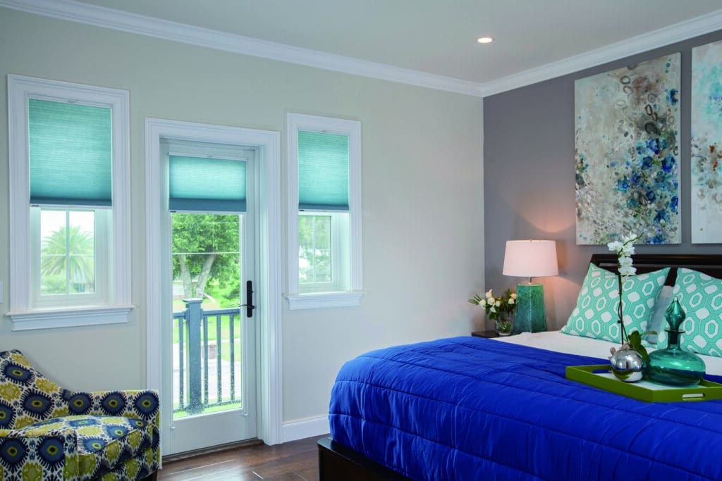 Bedroom with teal honeycomb blinds half-extended in an Adelaide home, offering privacy and natural light.
