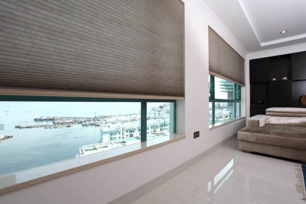 Modern living room with large beige honeycomb blinds in an Adelaide waterfront apartment.